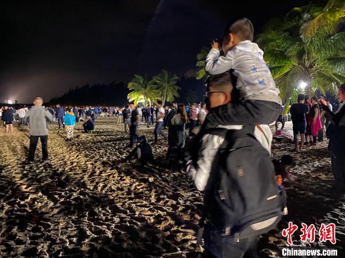 一位兒童坐著父親的肩上用望遠(yuǎn)鏡觀看文昌航天發(fā)射場。凌楠 攝