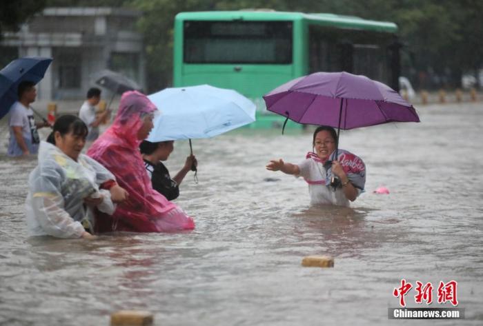 7月20日，鄭州遭遇強(qiáng)降雨，在經(jīng)三路、農(nóng)業(yè)路上，市民互相幫助走在齊腰深的積水里。 圖片來源：視覺中國