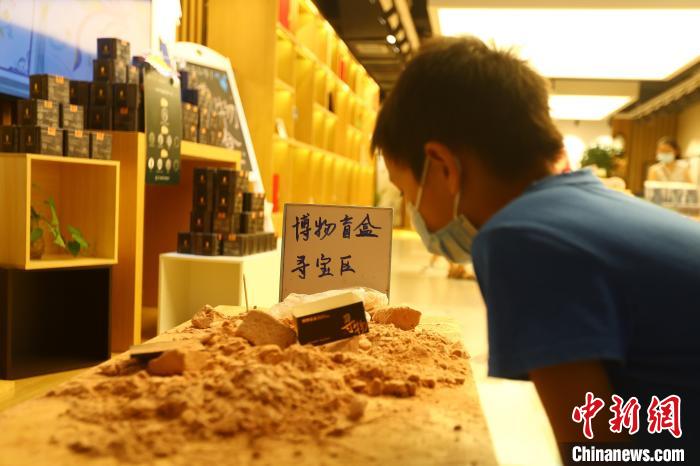 圖為在江西省博物館天工坊，一名小男孩端詳著已經(jīng)拆解完畢的“考古盲盒”現(xiàn)場(chǎng)?！⒄祭?攝